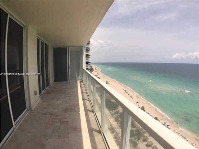 balcony featuring a water view and a beach view