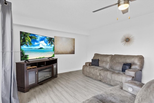 living room featuring light wood-style flooring, baseboards, and ceiling fan