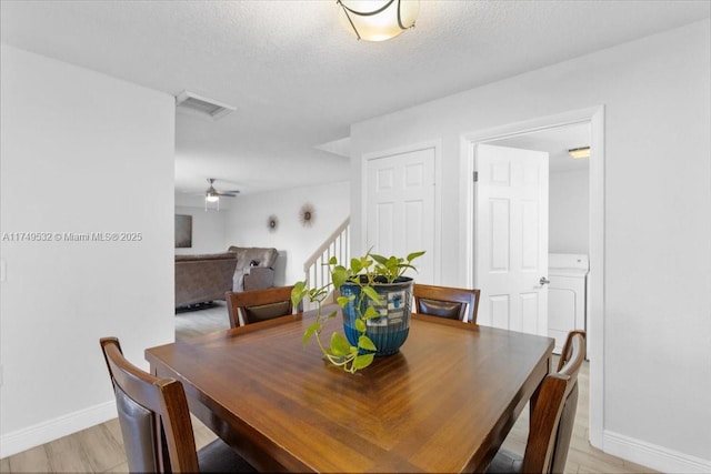 dining space featuring washer / dryer, baseboards, a textured ceiling, and light wood finished floors