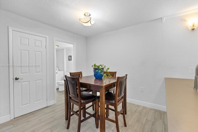 dining room with wood tiled floor, baseboards, and a textured ceiling