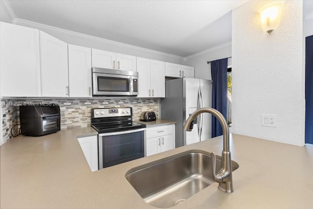 kitchen with appliances with stainless steel finishes, white cabinets, a sink, and light countertops