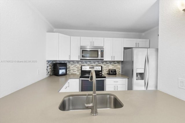 kitchen featuring stainless steel appliances, white cabinets, light countertops, ornamental molding, and tasteful backsplash