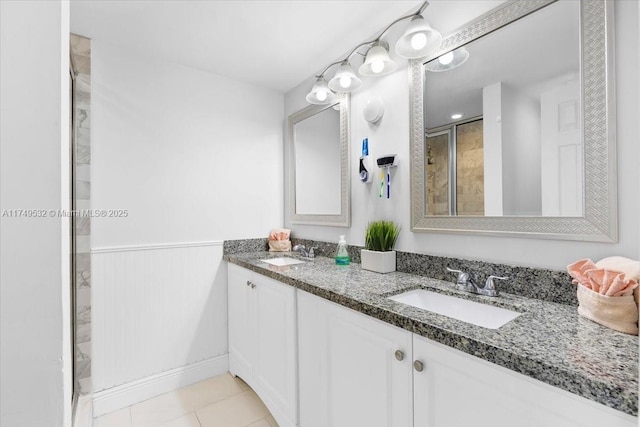 full bath with double vanity, a wainscoted wall, tile patterned flooring, and a sink