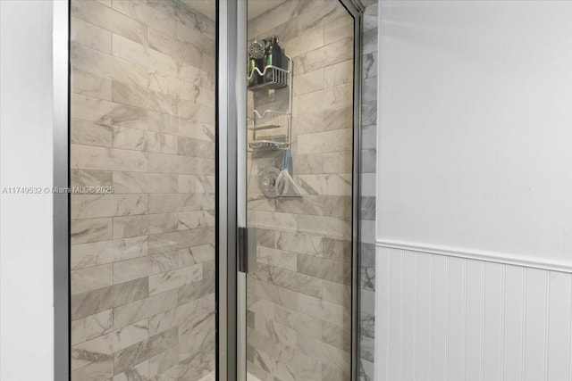 full bath with a wainscoted wall and a stall shower