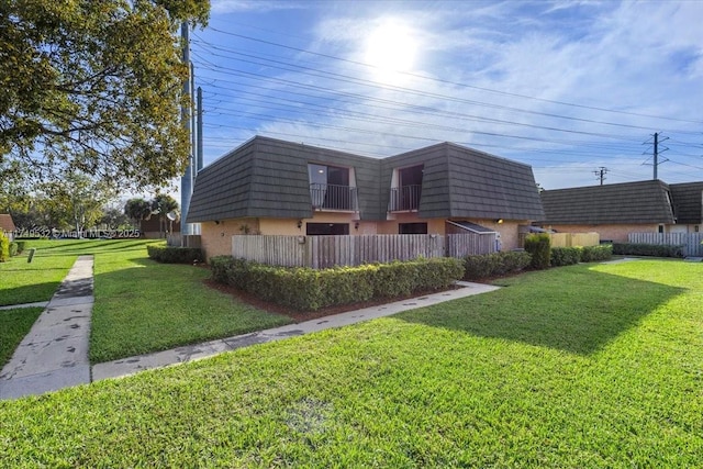 view of property exterior with a yard, fence, and mansard roof