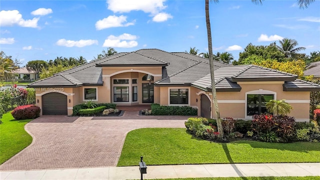 view of front of house with decorative driveway, stucco siding, a garage, a tiled roof, and a front lawn