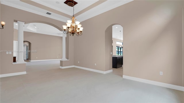 spare room featuring baseboards, a tray ceiling, and arched walkways