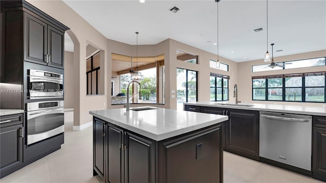 kitchen with decorative light fixtures, a sink, an island with sink, and stainless steel dishwasher