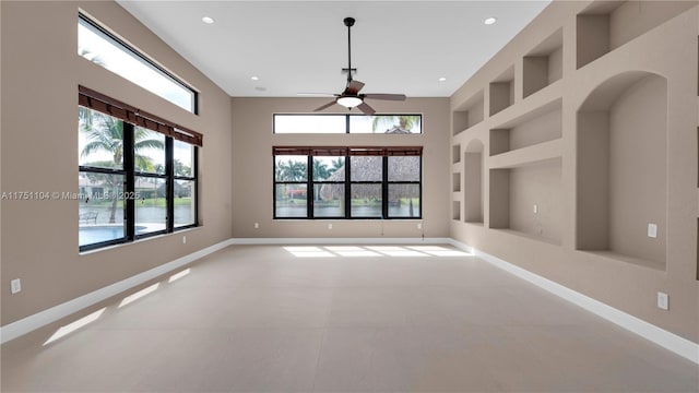 empty room with built in features, recessed lighting, a healthy amount of sunlight, and baseboards