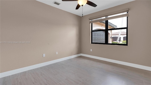 spare room with ceiling fan, light wood-style floors, visible vents, and baseboards