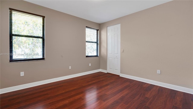 spare room with dark wood-type flooring and baseboards