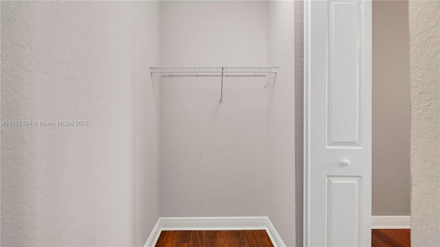 walk in closet with wood finished floors