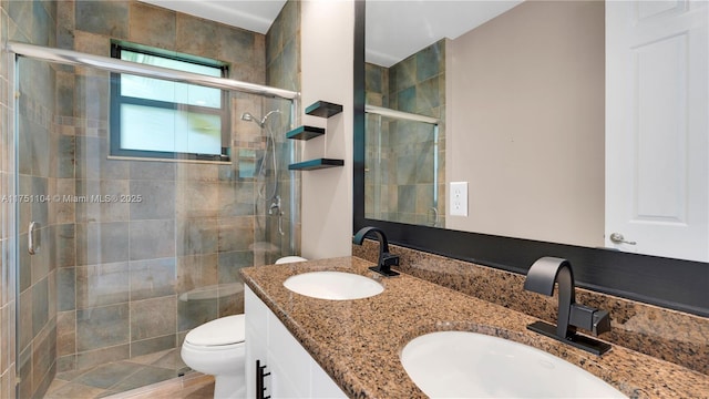 bathroom featuring a sink, a shower stall, toilet, and double vanity