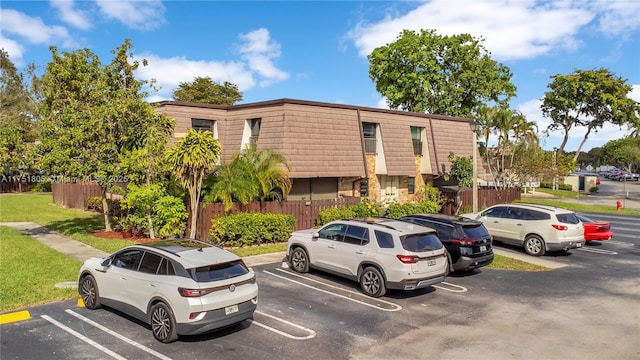 view of building exterior featuring uncovered parking and fence