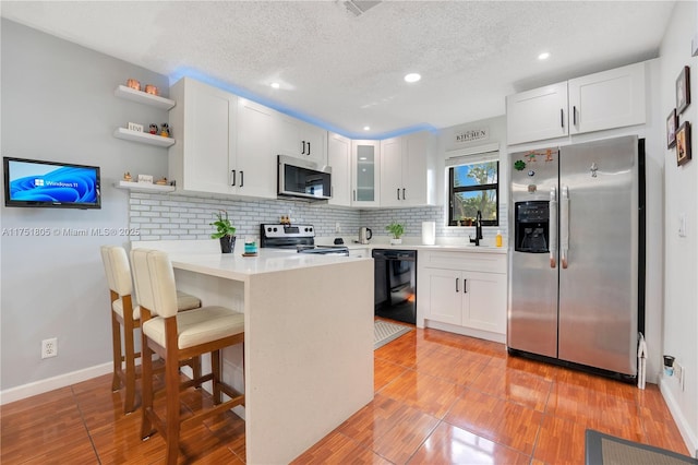 kitchen featuring white cabinets, glass insert cabinets, stainless steel appliances, and light countertops