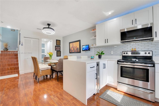 kitchen with light countertops, appliances with stainless steel finishes, open shelves, and white cabinetry