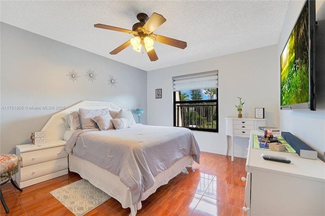 bedroom featuring baseboards, a ceiling fan, a textured ceiling, and wood finished floors
