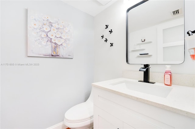 bathroom with toilet, vanity, and visible vents