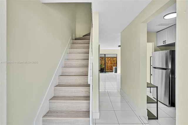 staircase with tile patterned flooring, visible vents, and baseboards