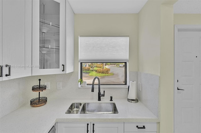 kitchen featuring backsplash, a sink, and white cabinetry