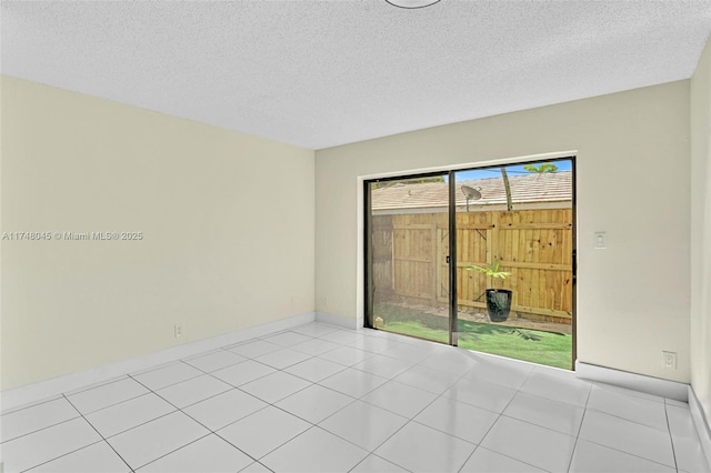 spare room with light tile patterned floors, baseboards, and a textured ceiling