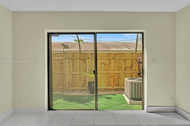 doorway to outside featuring light tile patterned flooring, a textured ceiling, and baseboards