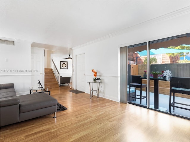 living area featuring baseboards, visible vents, stairway, ornamental molding, and wood finished floors