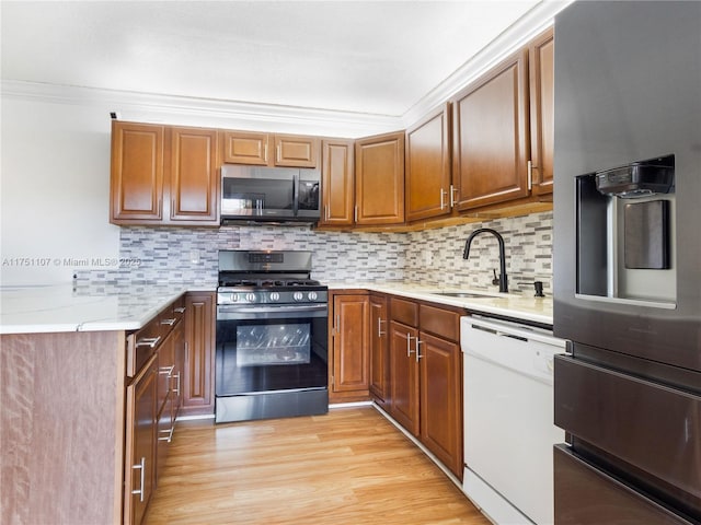 kitchen featuring a sink, light wood-style floors, light countertops, appliances with stainless steel finishes, and backsplash