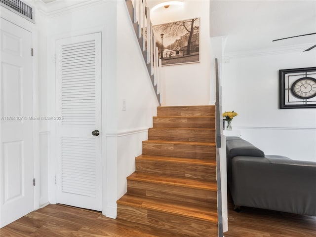 stairs featuring ornamental molding, visible vents, and wood finished floors