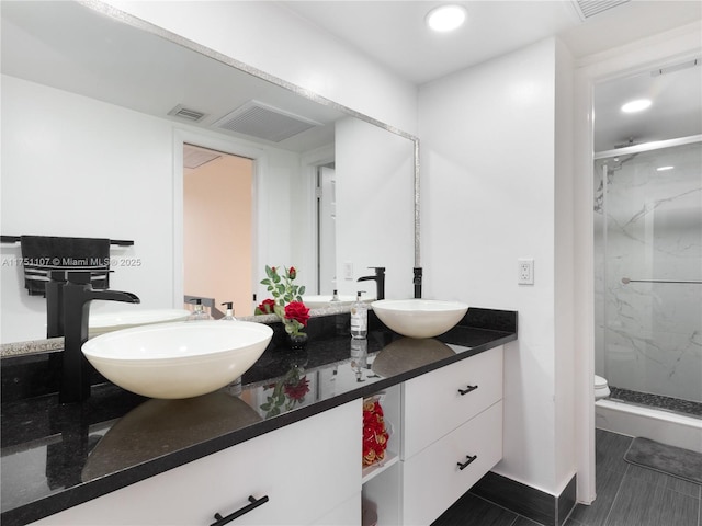 full bathroom with a sink, double vanity, a marble finish shower, and visible vents