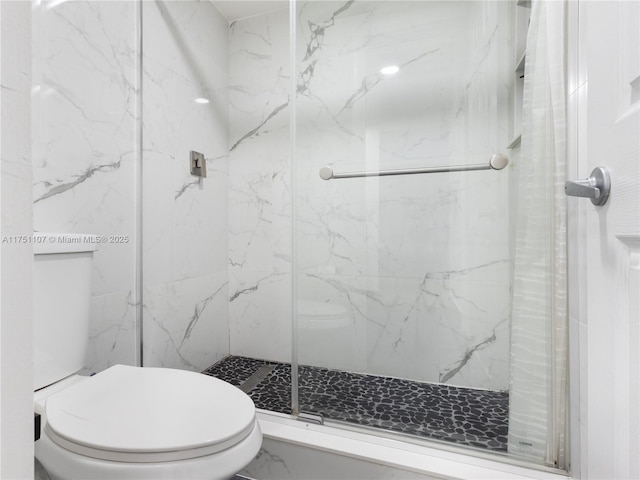 bathroom with toilet and a marble finish shower