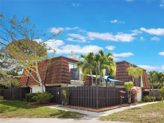 view of front of home with a fenced front yard and mansard roof