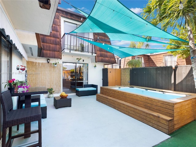 view of patio with a balcony, a jacuzzi, and fence