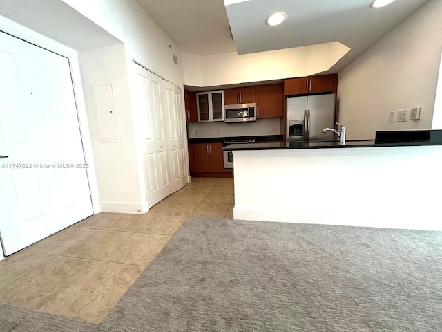 kitchen featuring light tile patterned floors, a sink, baseboards, appliances with stainless steel finishes, and dark countertops