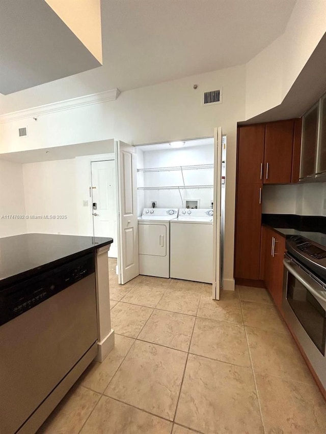 kitchen with washing machine and clothes dryer, light tile patterned floors, stainless steel appliances, dark countertops, and visible vents