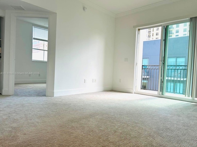 empty room with ornamental molding, light colored carpet, and baseboards