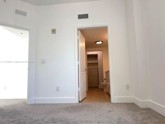 interior space featuring ensuite bath, visible vents, and light colored carpet