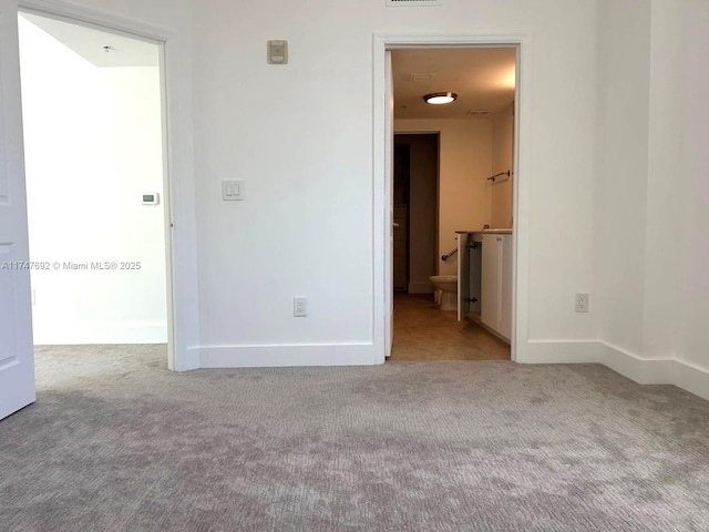 unfurnished room with light colored carpet and baseboards