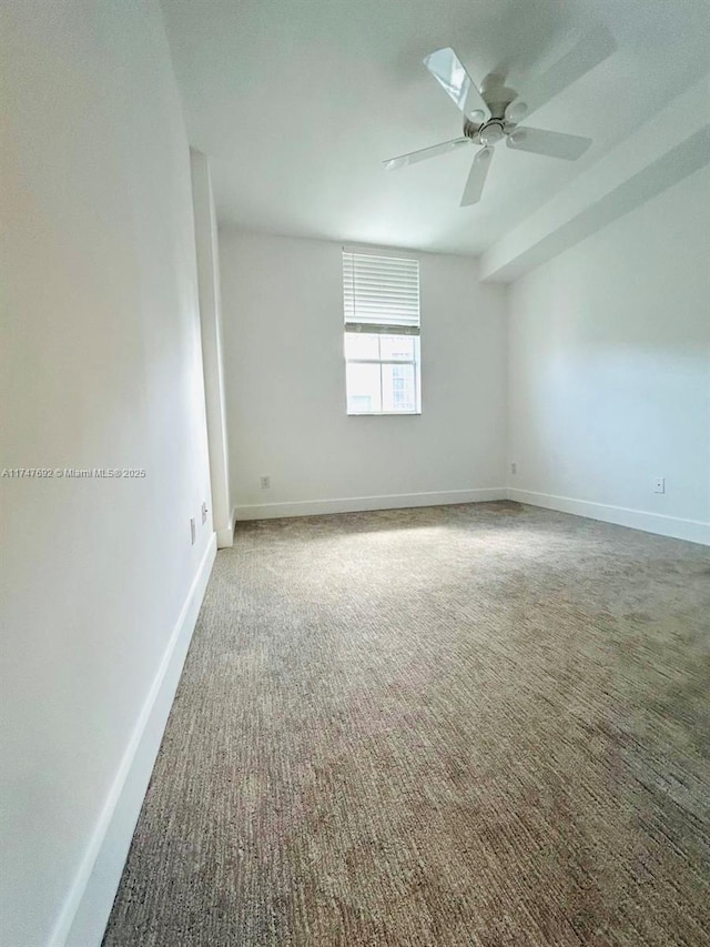 spare room with ceiling fan, dark carpet, and baseboards