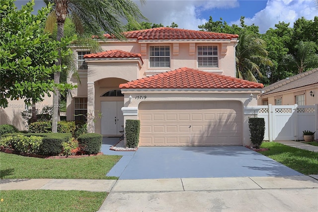 mediterranean / spanish-style house featuring stucco siding, concrete driveway, fence, a garage, and a tiled roof