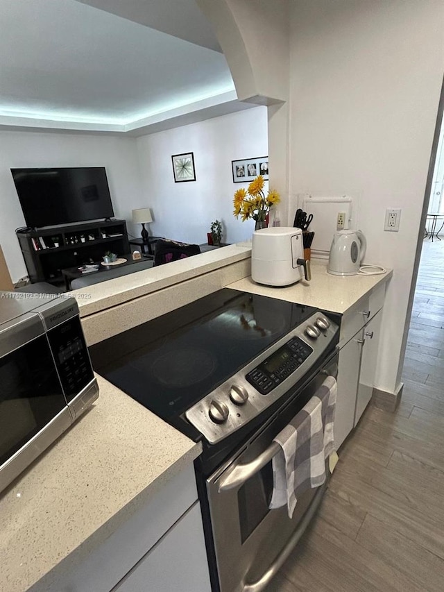 16900 NE 14th Ave Unit 209, Miami, FL 33162 - kitchen featuring stainless steel appliances, wood finished floors, light countertops, white cabinets, and arched walkways