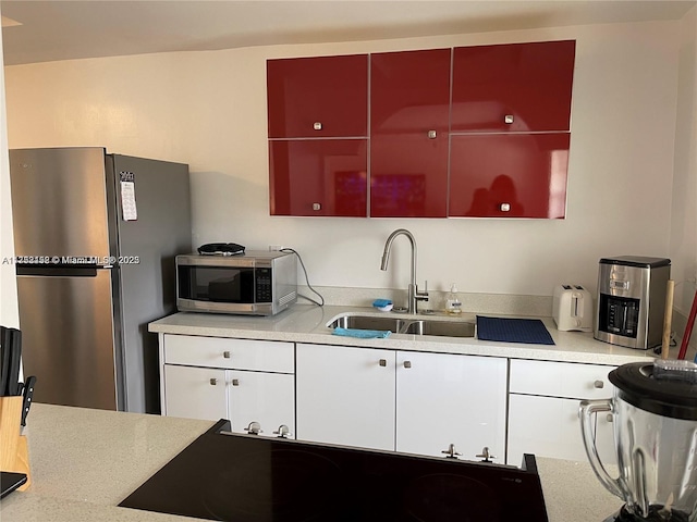 kitchen featuring stainless steel appliances, modern cabinets, a sink, and light countertops