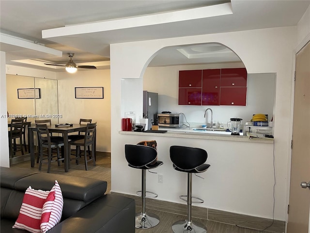 kitchen with arched walkways, ceiling fan, stainless steel appliances, light countertops, and a sink