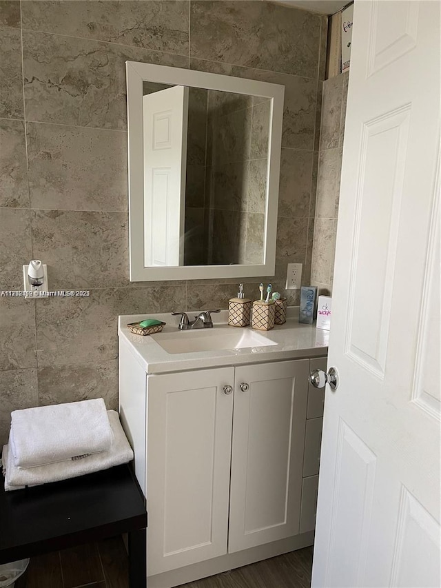 bathroom with wood finished floors, vanity, and tile walls