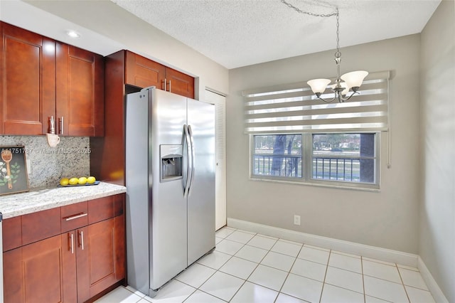 kitchen with stainless steel refrigerator with ice dispenser, a textured ceiling, an inviting chandelier, light tile patterned flooring, and decorative backsplash