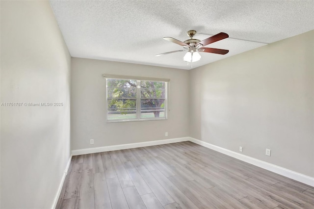 empty room with light wood-type flooring, a textured ceiling, baseboards, and a ceiling fan