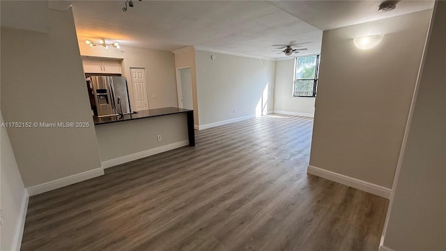 unfurnished living room featuring dark wood-style floors, crown molding, ceiling fan, and baseboards