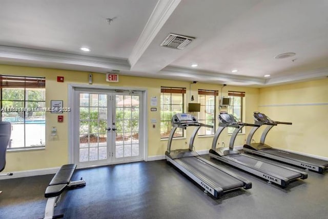 exercise room with a tray ceiling, visible vents, crown molding, and baseboards