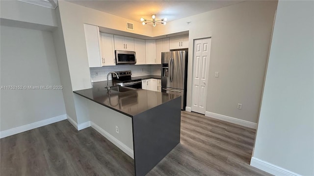 kitchen featuring visible vents, white cabinets, dark countertops, appliances with stainless steel finishes, and a peninsula