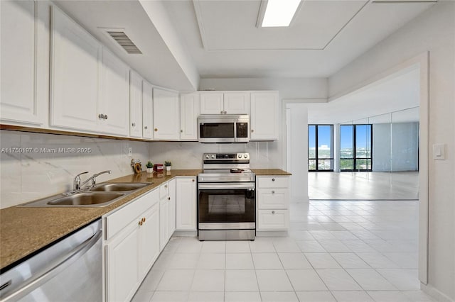 kitchen with stainless steel appliances, white cabinets, a sink, and visible vents